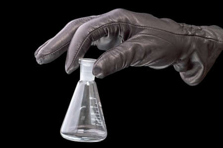 Hand in black leather glove with chemical glass bulb. Isolated on a black background