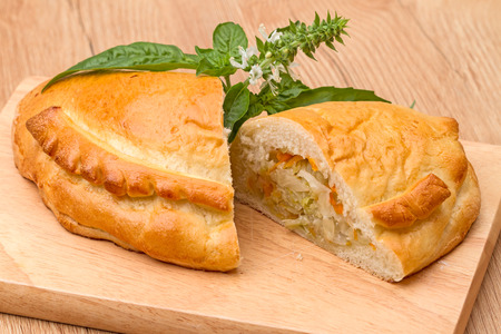 The two halves of the pie with cabbage on the kitchen board and basil
