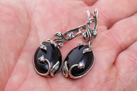 Silver earrings with  black agate on palm closeupの写真素材