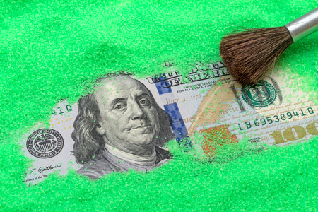 One hundred US dollar in green sand and brushの写真素材