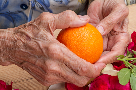 Hands of the old woman with ripe orangeの写真素材