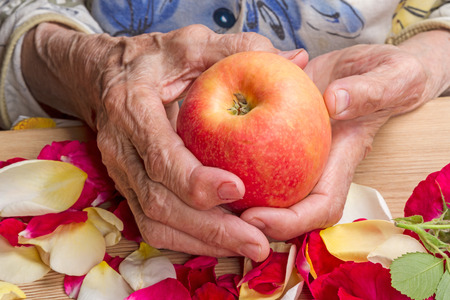Hands of the old woman with a ripe appleの写真素材
