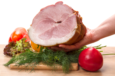 Big piece of pork loin in hand and fresh vegetables on white backgroundの写真素材