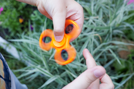 A fidget spinner is a toy that consists of a bearing in the center of a multi-lobed flat structure made from metal or plastic designed to spin along its axis with little effort.の写真素材