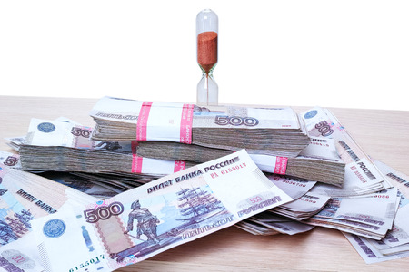 ime is money. Hourglass and pile of Russian money
