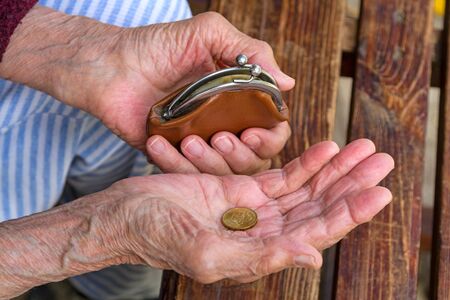 An old woman with a purse and a coin on her palmの写真素材