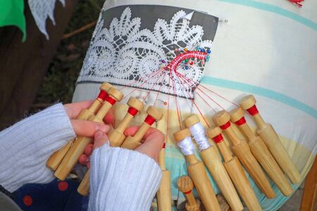 Hands of the girl weave lace with the help of a bobbinの写真素材