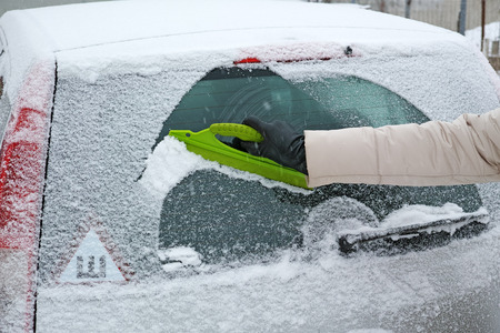 Winter car - woman removes from a back glass a scraperの写真素材