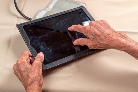 Compact tablet computer in the hands of an elderly womanの写真素材