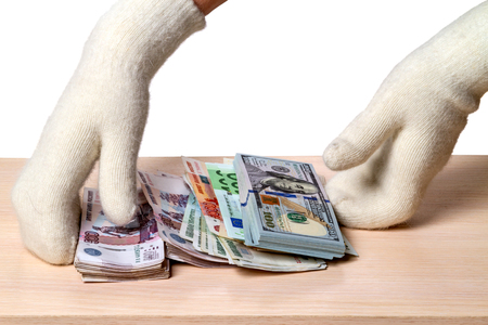 Hands in white knitted mittens and a variety of paper moneyの写真素材