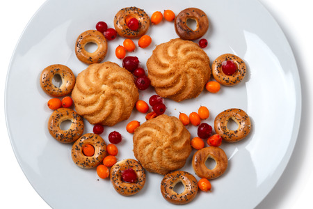 Sweet pastry (shortbread and bagel with poppy seeds) and frozen berries on a white plateの写真素材
