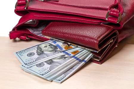 A purse with a hundred dollar bills in a bag on a tableの写真素材