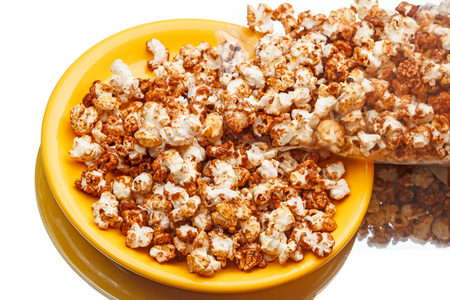 Sweet popcorn with syrup on a yellow plateの写真素材