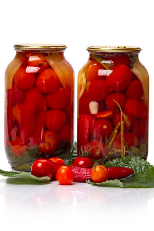 Two glass jars of canned tomatoes and fresh vegetable gradients isolated on white background. A series of canned foodの写真素材