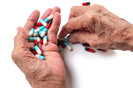 Old woman's hands and pills on white backgroundの写真素材