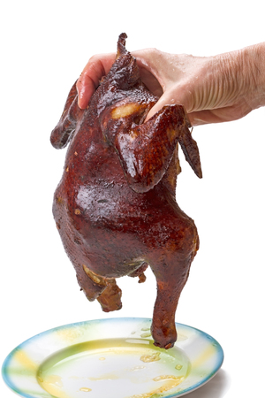 Fat smoked chicken in hand isolated on white backgroundの写真素材
