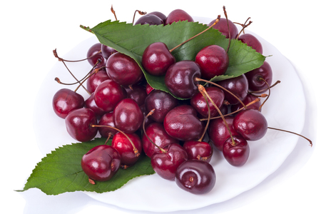 Ripe maroon cherry on a plate isolated on white backgroundの写真素材