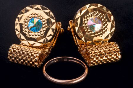 Gold Cufflinks and wedding ring on a black backgroundの写真素材