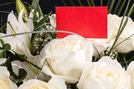 Red business card in a bouquet of white roses. Copy spaceの写真素材