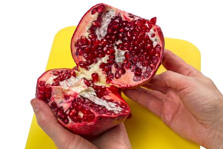 Two halves of a pomegranate in the hands on white backgroundの写真素材