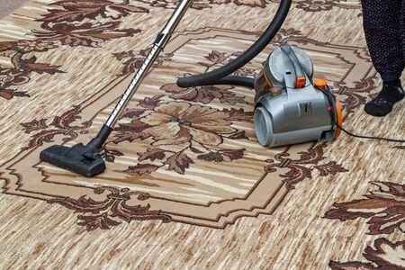 Woman a vacuum cleaner cleans an old  carpet palaceの写真素材
