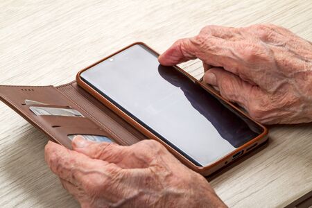 Hands of an old woman with smartphone