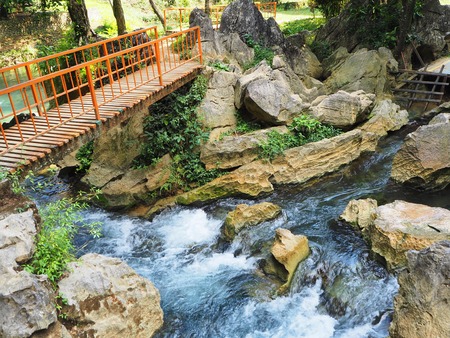 Orange bridge to cross a beautiful and colorful little river in Vang Vieng, Laos. The water smoothly...