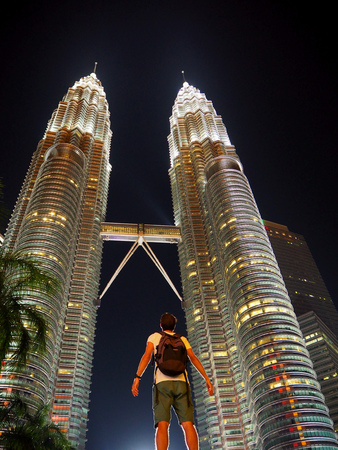 Astonished traveler looking up to the illuminated Petronas twin towers in Kuala Lumpur in the middle of the night. The nice black background makes the towers shine even moreのeditorial素材