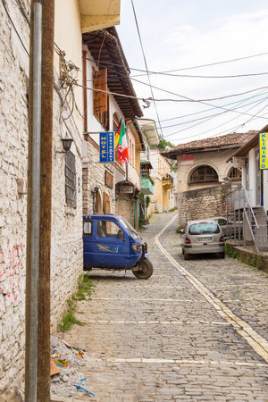 Berat, Albania- 30 June 2014: Narrow, cobbled streets with vehicles in the historical town Berat. Ottoman architecture in Albania, Unesco World Heritage Site. Berat city of a thousand windows.のeditorial素材