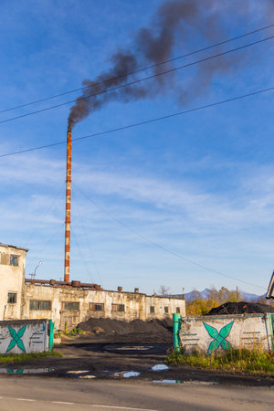 Milkovo, Kamchatka, Russia- 27 September 2014: View of the building of a combined heat and power plant with coal storage in Milkovo, town in the center of the Kamchatka Peninsula. Smoke rising from the high chimney.のeditorial素材