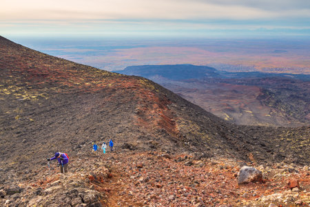 Kamchatka Peninsula, Russia- 28 September 2014: Group of hikers walking on a mountain, Volcanic area, hillside covered with stones.のeditorial素材