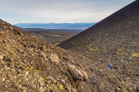 Unnamed, extinct volcano on the Kamchatka Peninsula in the far east of Russia. Black, volcanic stone with green moss. Snow- capped mountain in the background.の写真素材