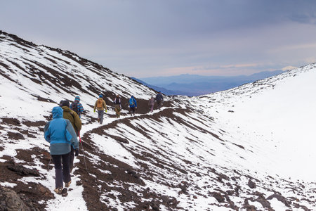 Kamchatka Peninsula, Russia- 29 September 2014: Group of hikers walking on a mountain, Volcanic area, hillside covered with snow.のeditorial素材