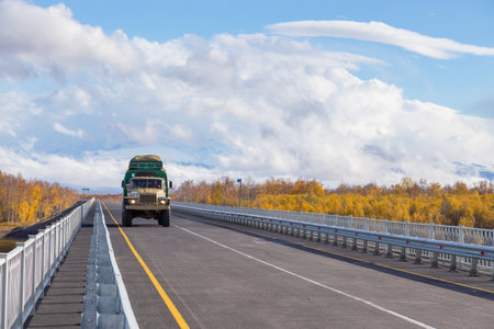 Unnamed Road, Kamchatka Peninsula, Russia- 02 October 2014: Russian off-road extreme expedition truck. Asphalt road on the bridge over Kamchatka River. Mount Ostry Tolbachik covered by clouds.のeditorial素材