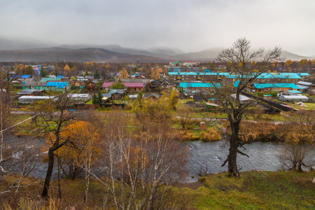 Esso, Kamchatka Peninsula, Russia- 02 October 2014: :View of the village Esso, blue roofs houses. Bystra River in first plan, mountain in the background.のeditorial素材