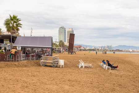 Barcelona, Spain- 09 November 2014: Restaurants and people on the most fashionable Barceloneta Beach. Modern building in the background.のeditorial素材