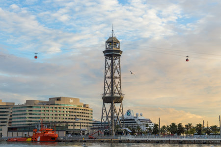 Barcelona, Spain- 10 November 2014: Teleferic del Port , a steel truss tower, part of the Port Vell Aerial Tramway near the Port of Barcelona. Cabins leaving Torre Jaume I, sunset.のeditorial素材