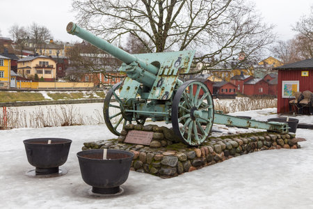 Porvoo, Finland- 04 March 2015: Porvoo Continuation War Memorial Cannon - Static Artillery by the Porvoonjoki River. Old, historic town in the background.のeditorial素材