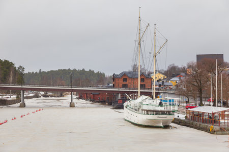 Porvoo, Finland- 04 March 2015: Sailing ship moored on the bank of the frozen Porvoonjoki River. Old, historic town in the background.のeditorial素材