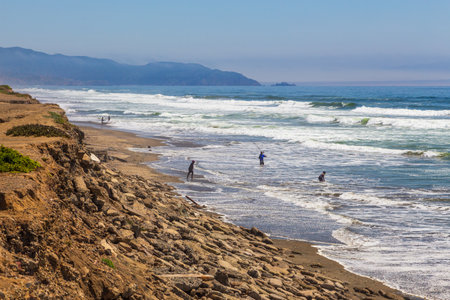 San Francisco, California, USA- 08 June 2015: People on the beach of the Pacific Ocean. Hills along the coast.のeditorial素材