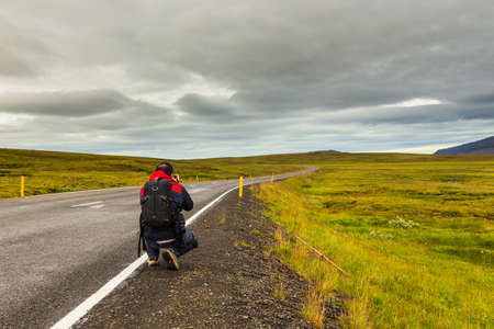 A man taking a picture on Pingvallavegur Road 36 Road in Iceland, Golden Circle.の写真素材