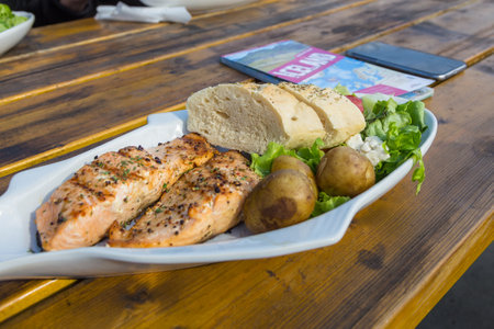 Husavik, Iceland- 25 August 2015: Grilled salmon with potatoes, a specialty of the region, served outside a local restaurant. Iceland map on the table.のeditorial素材