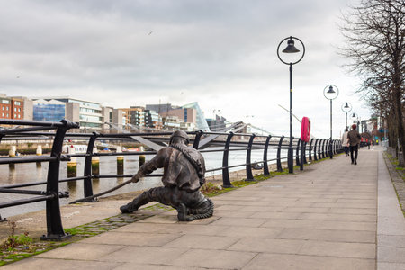 Dublin, Ireland - November 10, 2015: The Linesman sculpture by Dony McManus in the foreground of a Dublin cityscape from city quay.のeditorial素材