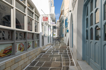 Chora, Ios Island, Greece- 20 September 2020: Narrow street of the old town with shops and restaurant. Traditional, withe architecture and a stone path with white joints.のeditorial素材