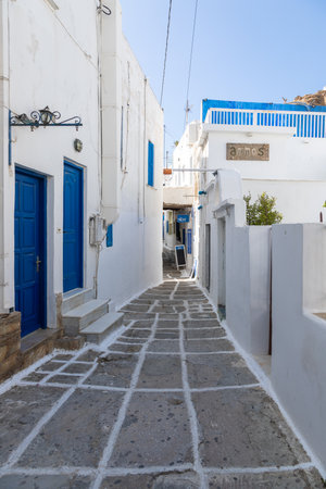 Chora, Ios Island, Greece- 20 September 2020: Narrow street of the old town with shops and restaurant. Traditional, withe architecture and a stone path with white joints.のeditorial素材