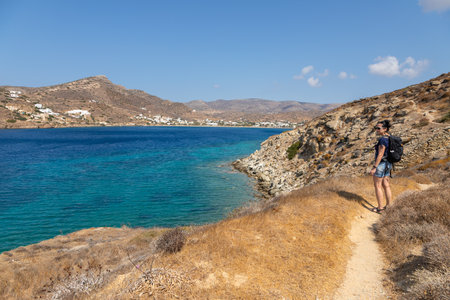 Greece, Ios Island, Chora- 22 September 2020: Woman on a path along the rocky coast of the Aegean Sea. Beautiful summer sunny day.のeditorial素材