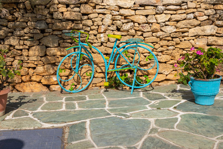 A blue and yellow bicycle leaning against a stone wall. Decoration of the local restaurant. Folegandros Island, Greece.の写真素材