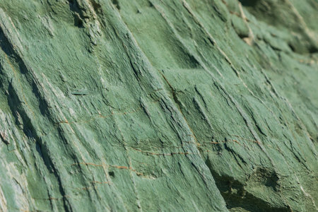 Turquoise green rock, background texture, natural stone off the coast of Folegandros island. Greece.