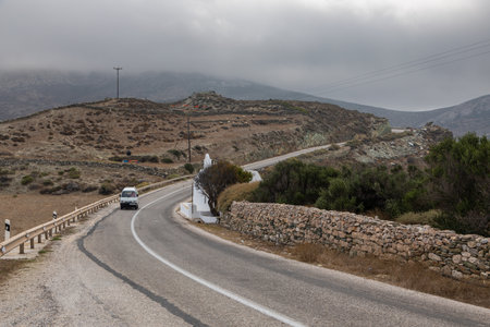 Folegandros Island, Greece - 24 September 2020: A small traditional Greek church by the road. Car on the road. Landscapes of the island of Folegandros.のeditorial素材