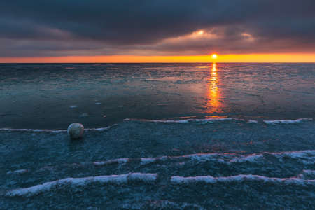 Beautiful sunset over the Bay of Gdansk in Jastarnia. Natural snow balls on the beach. Winter landscape. Poland.の写真素材